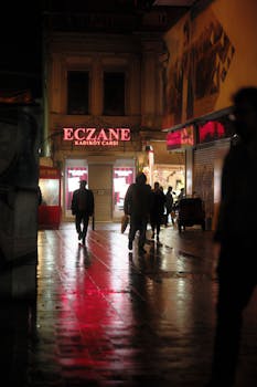 Moody street view in Kadıköy, Istanbul with walking pedestrians and store lights.