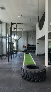 Spacious gym filled with modern exercise machines and a green training track.