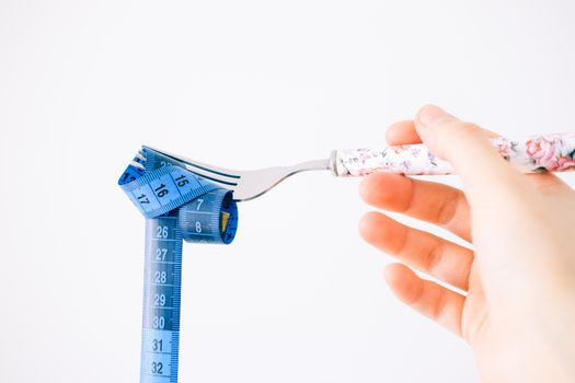 A floral-handled fork twirls a blue measuring tape, symbolizing diet and health.